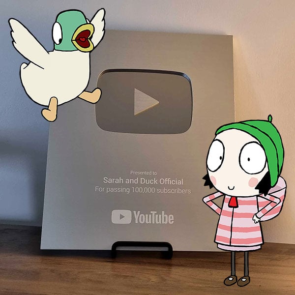 A YouTube Silver Play Button award sits on a stand, celebrating 100,000 YouTube subscribers, with cartoon characters of a duck and a girl added to the image.